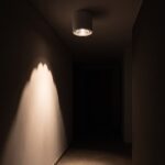 Plafonnier cylindre allumé la nuit, arc de lumière sur le mur d'un couloir