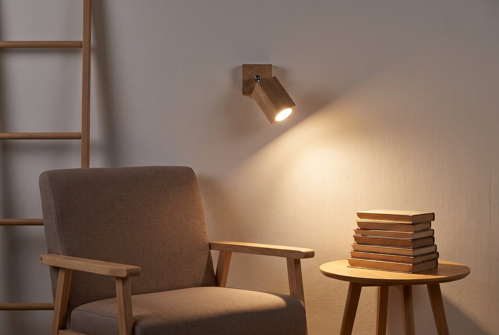 Applique murale spot en bois de chêne allumée au-dessus d'un fauteuil de lecture, ampoule GU10 en lumière chaude