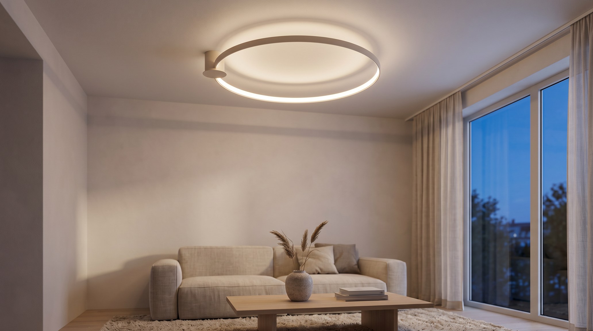 Plafonnier anneau LED beige allumé en blanc chaud dans un salon le soir, au-dessus d'un canapé en lin, avec une table basse en bois et des murs clairs