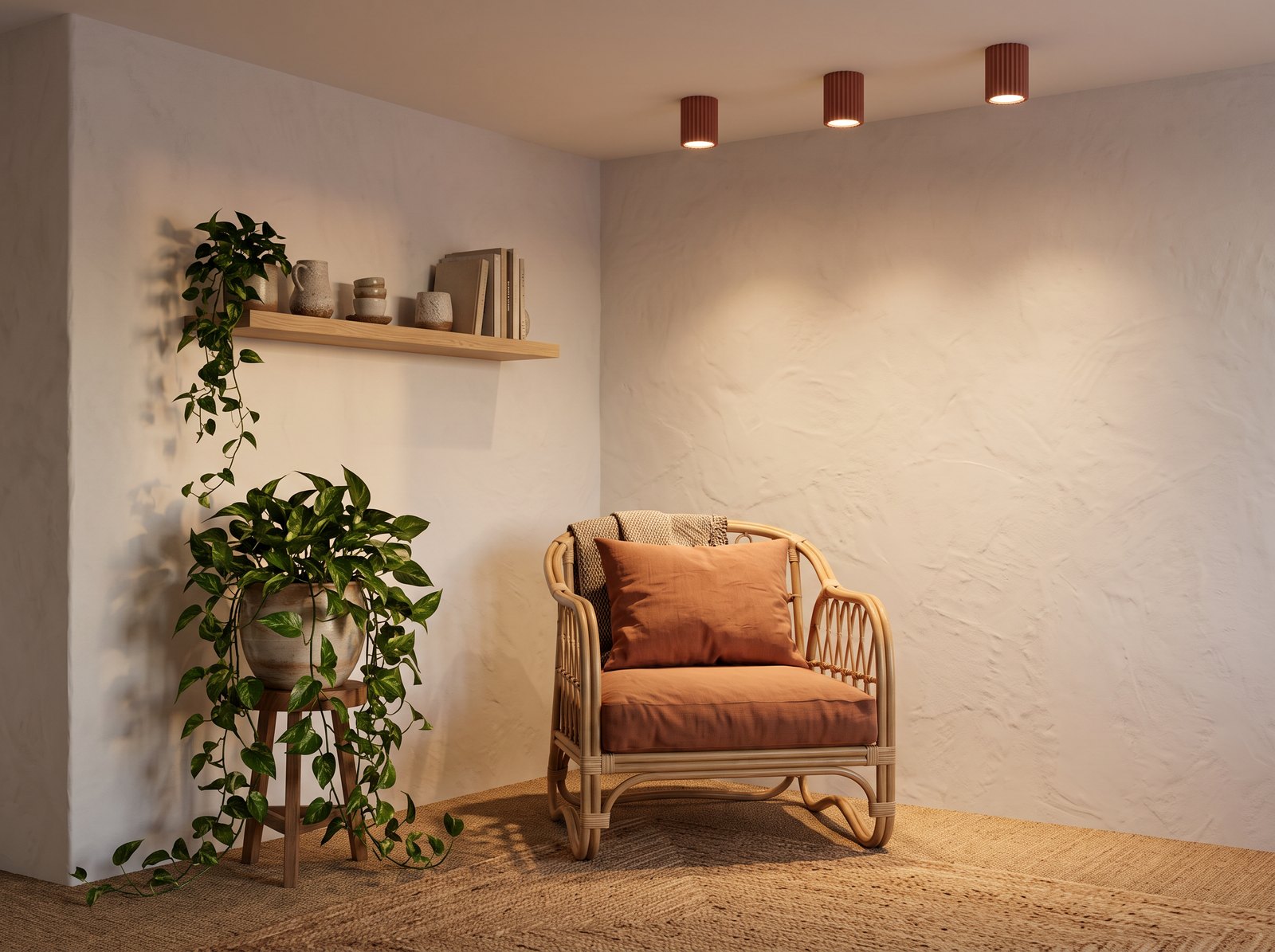 Coin lecture bohème avec un fauteuil en rotin, un coussin terracotta, un tapis en jute et trois plafonniers cylindriques cannelés terracotta allumés au plafond