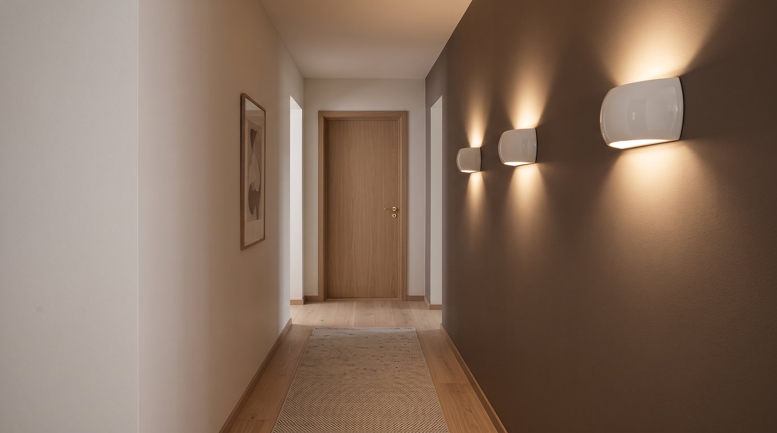 Trois appliques demi-lune en céramique blanche alignées dans un long couloir, éclairant le mur vers le haut et vers le bas