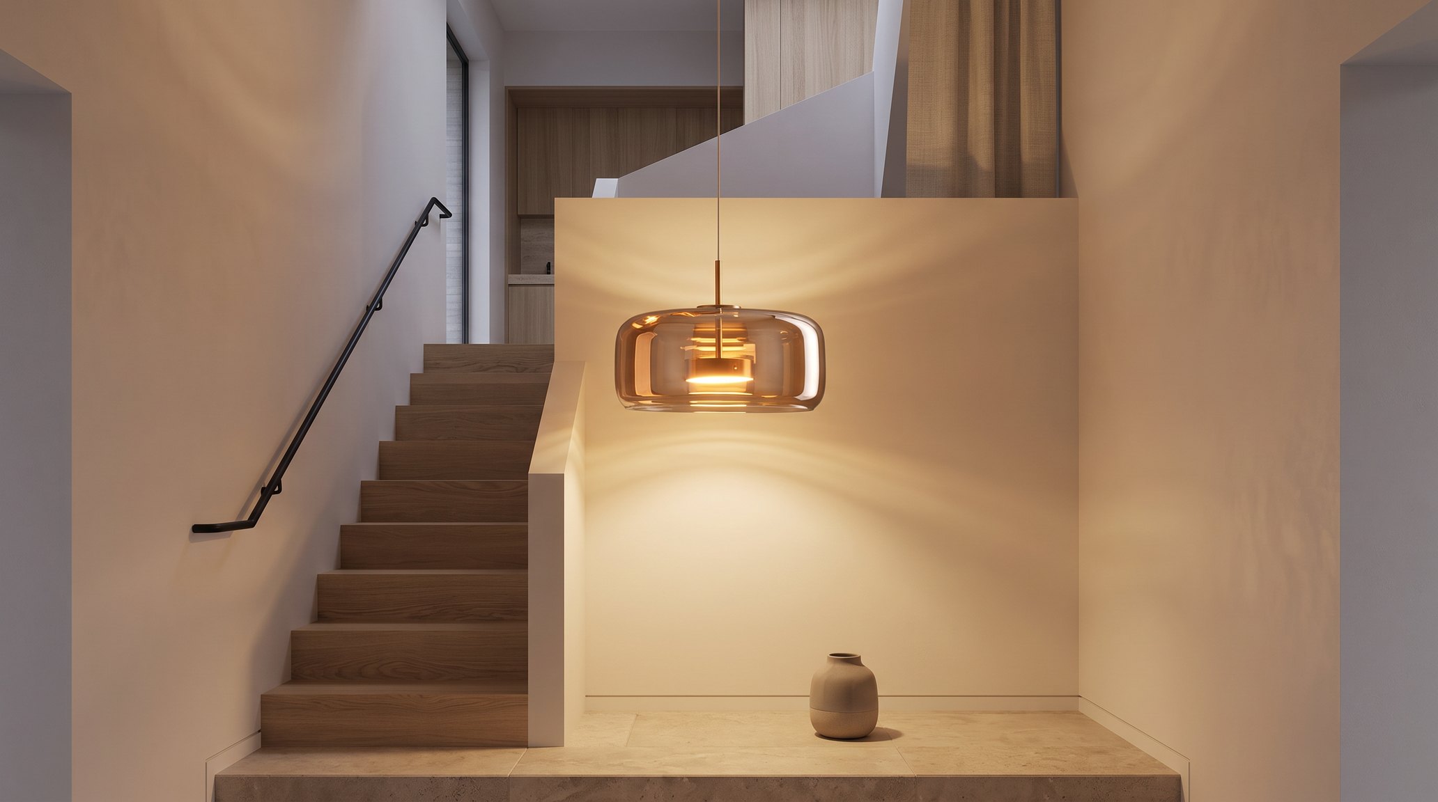 Cage d'escalier en chêne le soir, suspension ronde en verre fumé cognac et laiton allumée en blanc chaud au-dessus du palier, mur blanc cassé