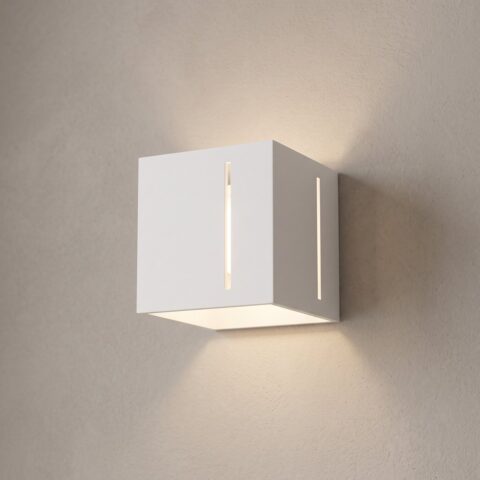Applique murale cube en aluminium blanc allumée sur un mur clair
